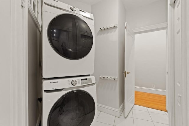 washroom with light tile patterned flooring and stacked washing maching and dryer