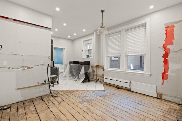 interior space with a baseboard heating unit, light hardwood / wood-style floors, and hanging light fixtures