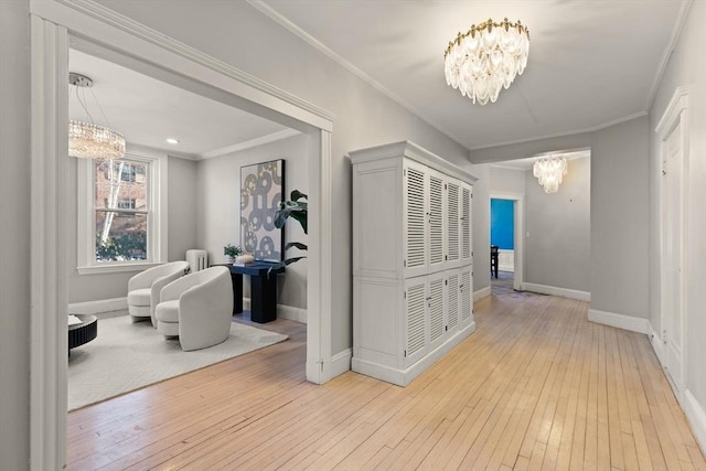 hall with crown molding, light wood-type flooring, and a notable chandelier