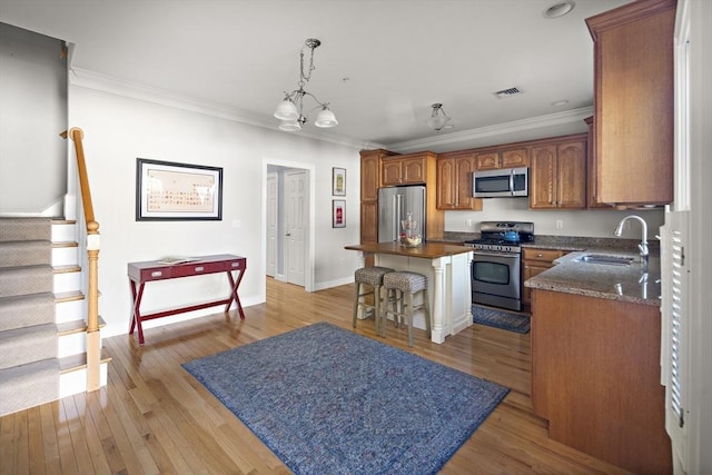 kitchen featuring a sink, appliances with stainless steel finishes, crown molding, and dark countertops