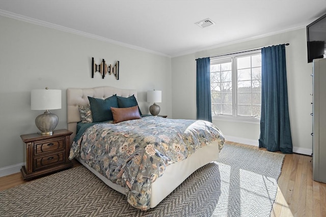 bedroom with baseboards, ornamental molding, light wood-style flooring, and visible vents