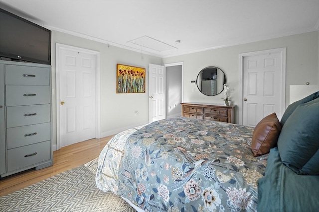 bedroom featuring crown molding, baseboards, attic access, and light wood finished floors
