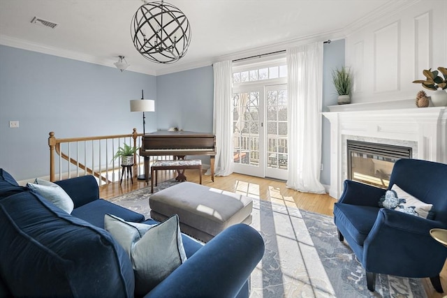 living room with a high end fireplace, ornamental molding, wood finished floors, and visible vents