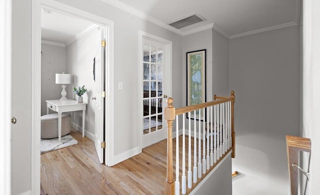 hall with crown molding, baseboards, an upstairs landing, and wood finished floors