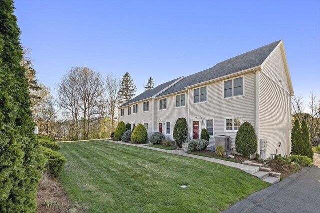 colonial inspired home with central AC unit and a front lawn
