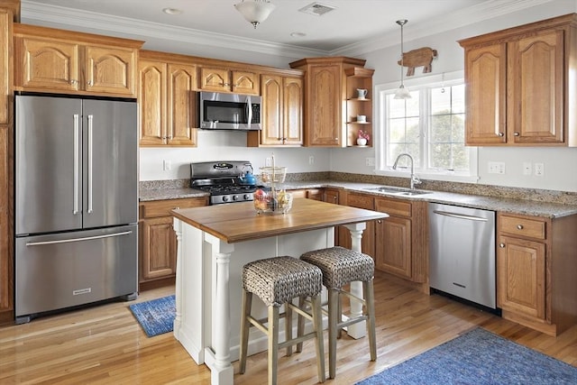kitchen featuring brown cabinetry, appliances with stainless steel finishes, light wood-type flooring, a sink, and butcher block counters