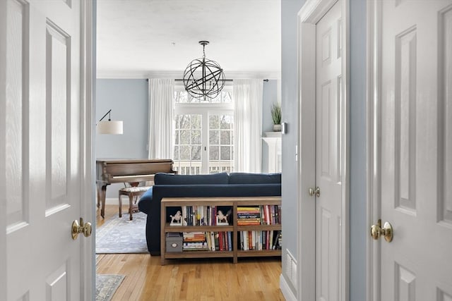interior space with baseboards, ornamental molding, light wood finished floors, and a notable chandelier