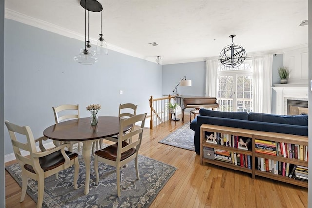 dining area with crown molding, baseboards, visible vents, and light wood finished floors
