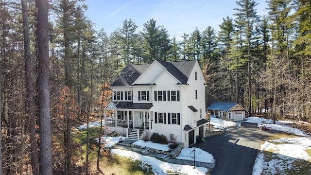 view of front of property featuring a forest view, aphalt driveway, covered porch, a garage, and a standing seam roof