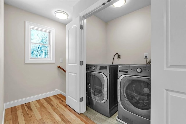 laundry area with light wood-type flooring, laundry area, washing machine and dryer, and baseboards