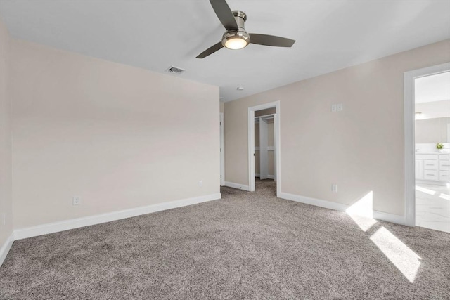 unfurnished bedroom featuring connected bathroom, carpet flooring, visible vents, baseboards, and a spacious closet