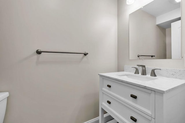 bathroom featuring toilet, baseboards, and vanity