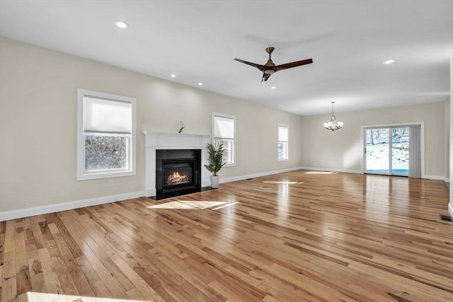 unfurnished living room with light wood finished floors, recessed lighting, a fireplace with flush hearth, and baseboards