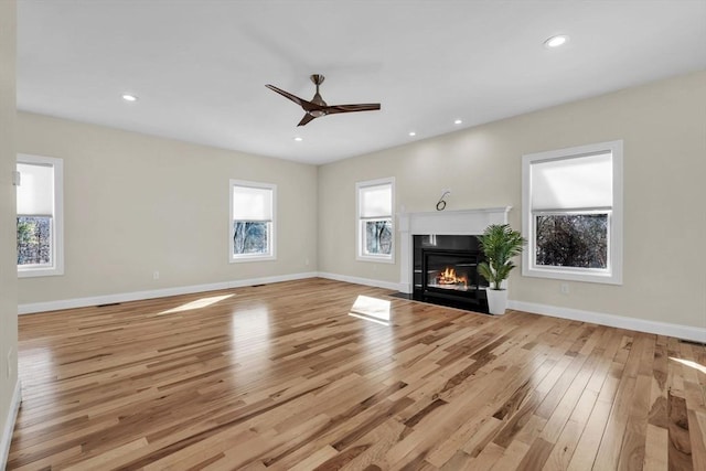 unfurnished living room with a fireplace with flush hearth, baseboards, and light wood-style flooring