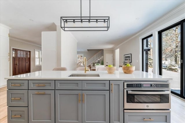 kitchen with hanging light fixtures, crown molding, sink, and gray cabinetry