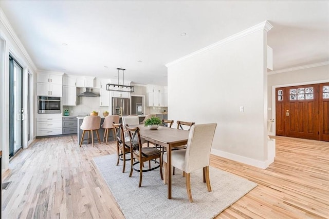 dining area with crown molding and light hardwood / wood-style floors