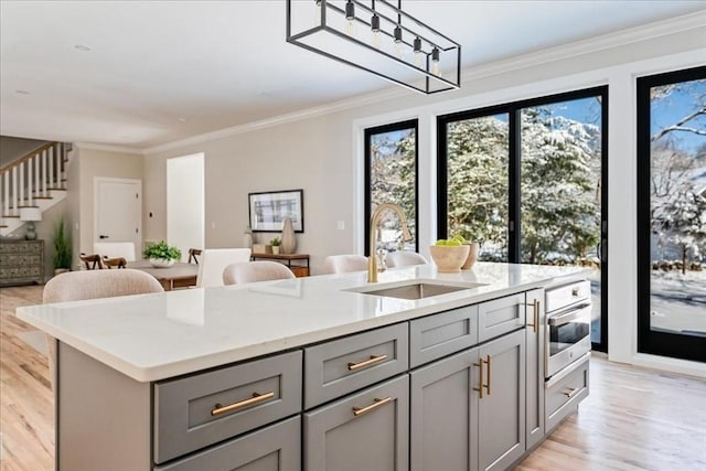 kitchen featuring plenty of natural light, sink, gray cabinetry, and a kitchen island with sink