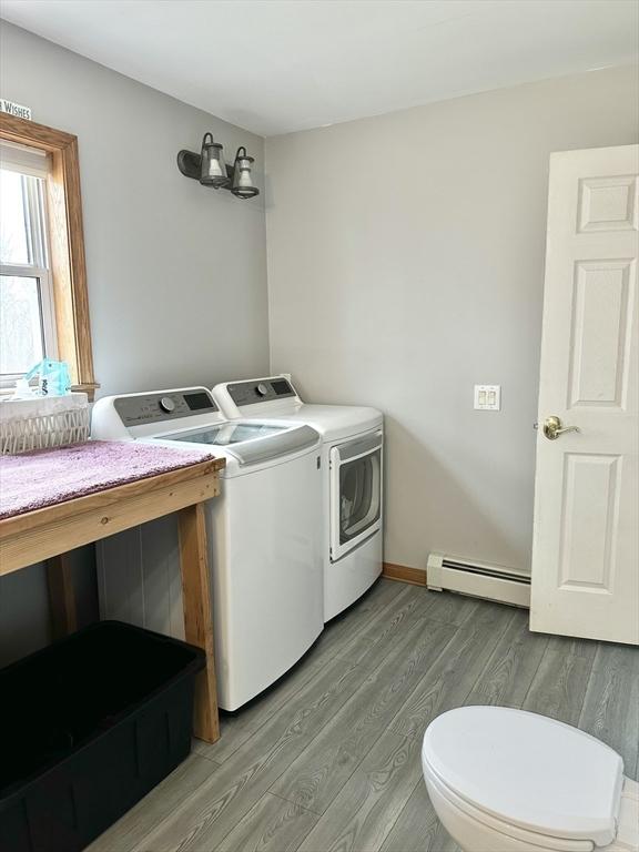 laundry room with laundry area, light wood finished floors, washing machine and dryer, and baseboard heating