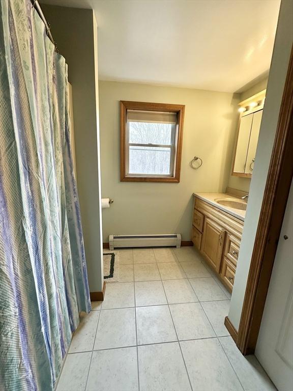 full bathroom featuring vanity, tile patterned floors, baseboards, and a baseboard radiator