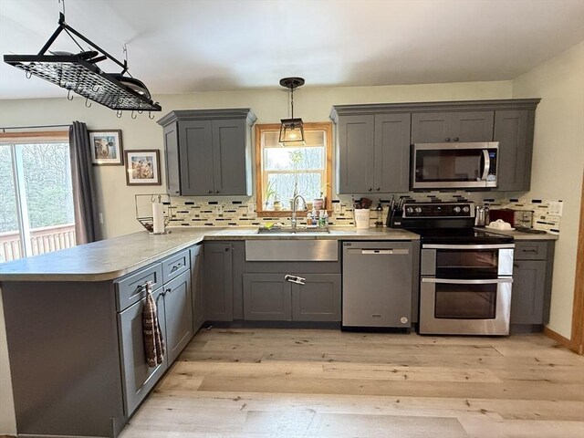 kitchen featuring a sink, stainless steel appliances, a peninsula, and a healthy amount of sunlight