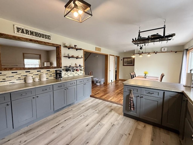 kitchen with plenty of natural light, decorative backsplash, gray cabinets, and light wood-style floors