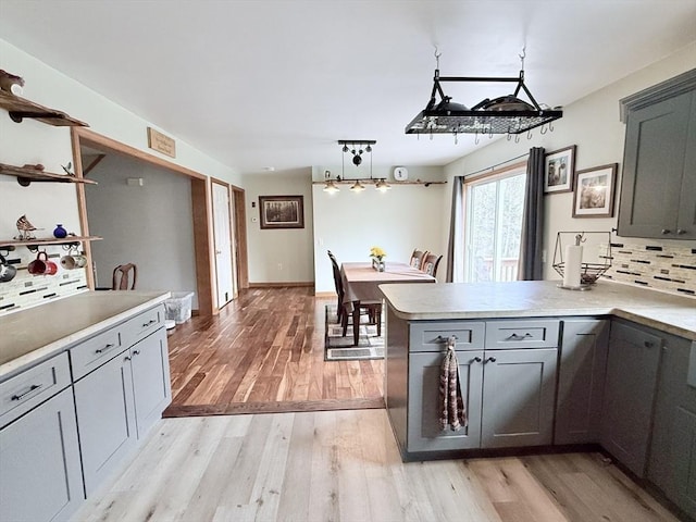 kitchen featuring light countertops, decorative backsplash, light wood-style floors, and a peninsula