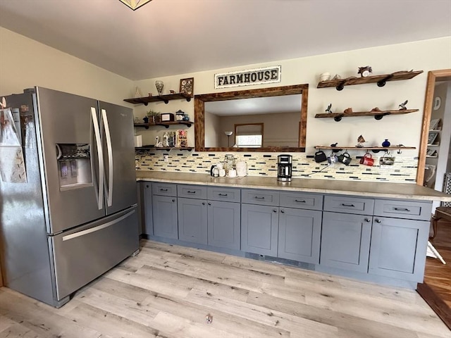 kitchen featuring light wood-style floors, gray cabinets, decorative backsplash, open shelves, and stainless steel fridge