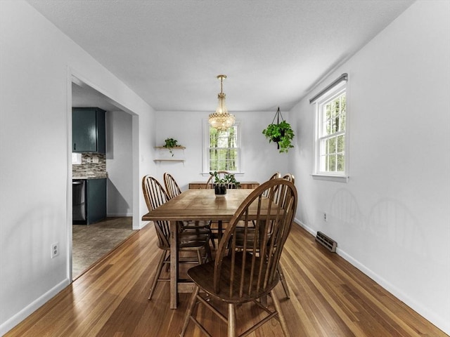 dining room with wood finished floors, baseboards, and a chandelier