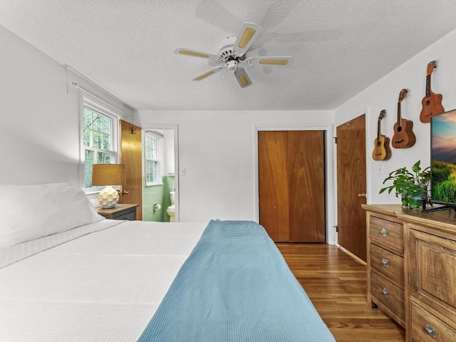 bedroom featuring wood finished floors, a textured ceiling, ensuite bath, and ceiling fan