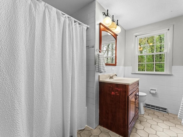 bathroom featuring tile walls, toilet, tile patterned flooring, wainscoting, and vanity