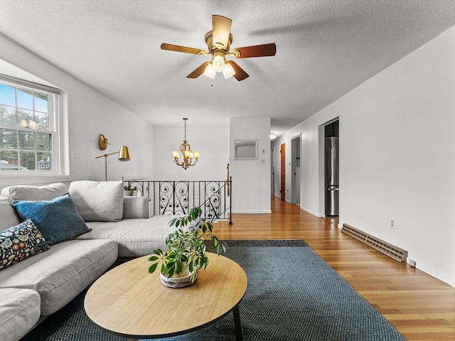 living room featuring a baseboard heating unit, a chandelier, wood finished floors, a ceiling fan, and a textured ceiling