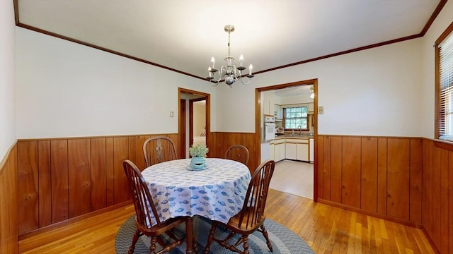 40 Revere St, Gloucester, MA 01930 - dining area featuring a wainscoted wall, wooden walls, a chandelier, light wood-type flooring, and crown molding