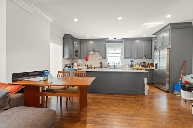 kitchen with stainless steel refrigerator with ice dispenser, dark hardwood / wood-style floors, ornamental molding, and gray cabinets