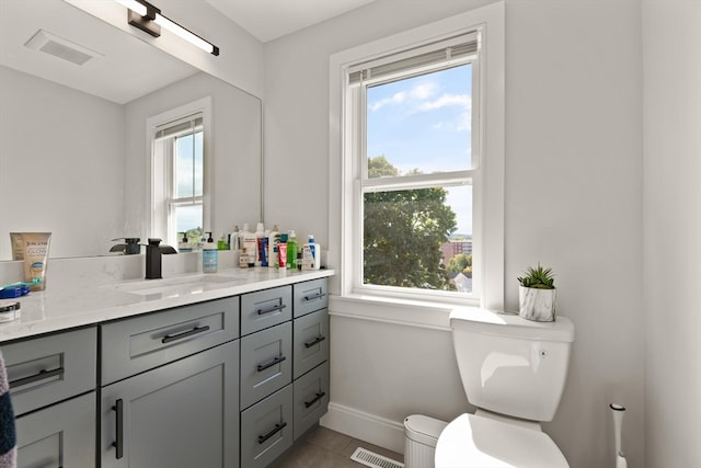 bathroom featuring vanity, tile patterned floors, a healthy amount of sunlight, and toilet