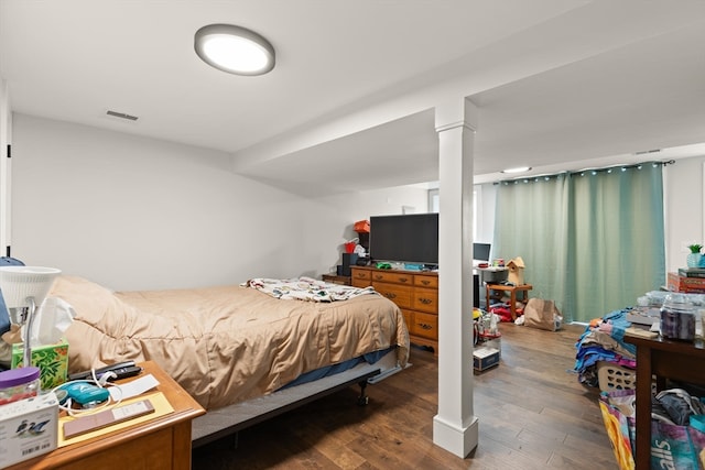 bedroom featuring ornate columns and dark hardwood / wood-style flooring