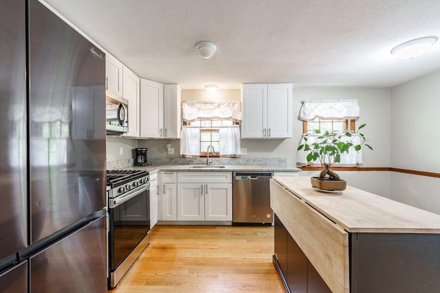 53 Greenleaf Dr, Hampden, MA 01036 - kitchen featuring stainless steel appliances, a sink, white cabinetry, light wood-style floors, and a textured ceiling