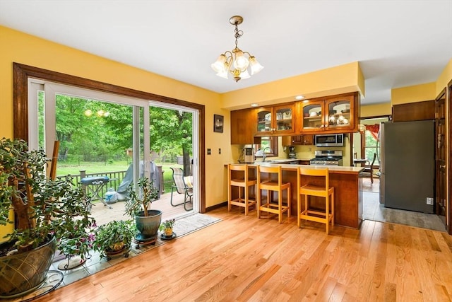 906 Clark St, Gardner, MA 01440 - kitchen featuring appliances with stainless steel finishes, light countertops, a peninsula, brown cabinets, and glass insert cabinets