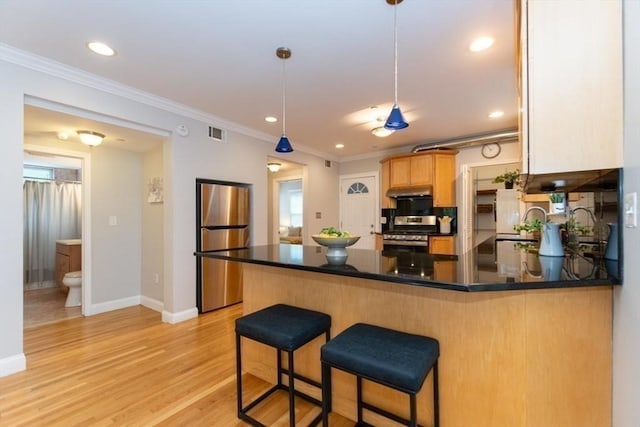 68 Line St Unit 2, Somerville, MA 02143 - kitchen featuring stainless steel appliances, a peninsula, under cabinet range hood, crown molding, and dark countertops