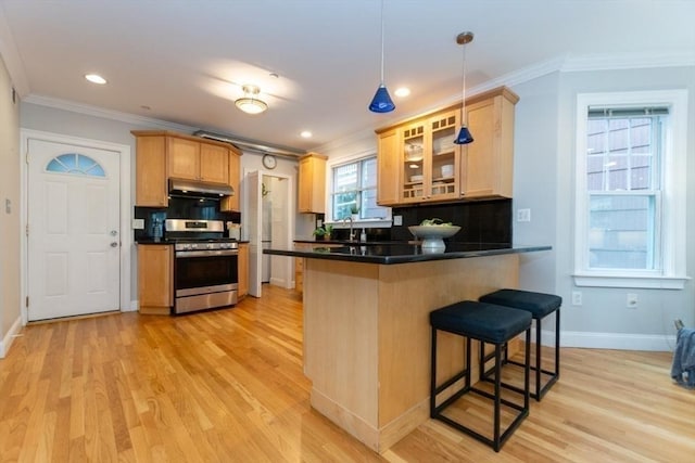 68 Line St Unit 2, Somerville, MA 02143 - kitchen featuring gas stove, under cabinet range hood, ornamental molding, a breakfast bar area, and light wood finished floors