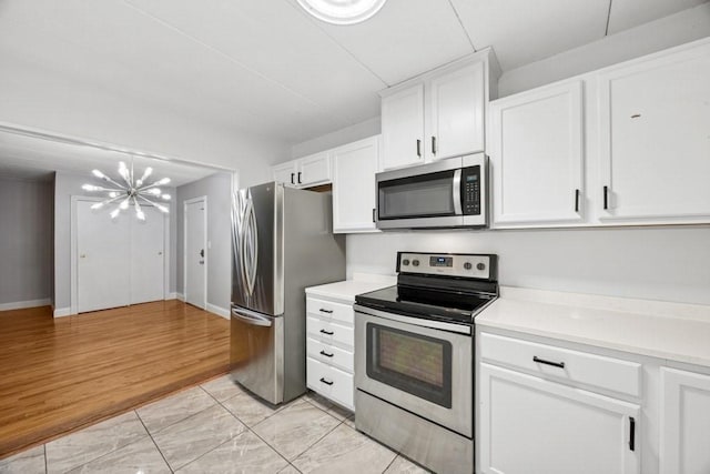 153 Milk St Unit 4, Westborough, MA 01581 - kitchen featuring appliances with stainless steel finishes, a chandelier, white cabinetry, and light countertops