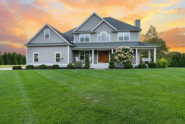 view of front of property with cooling unit, covered porch, and a lawn