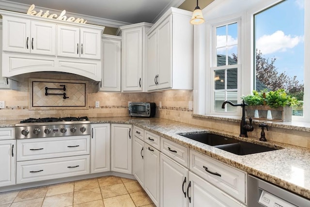 kitchen with appliances with stainless steel finishes, sink, white cabinets, and decorative light fixtures