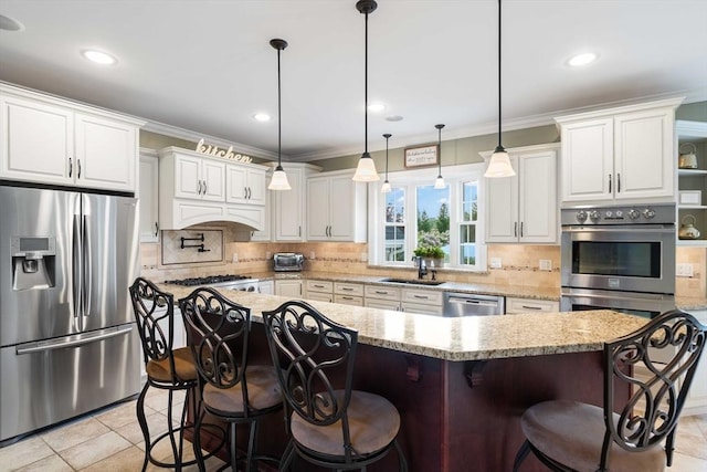 kitchen featuring appliances with stainless steel finishes, decorative light fixtures, white cabinetry, a kitchen bar, and a center island