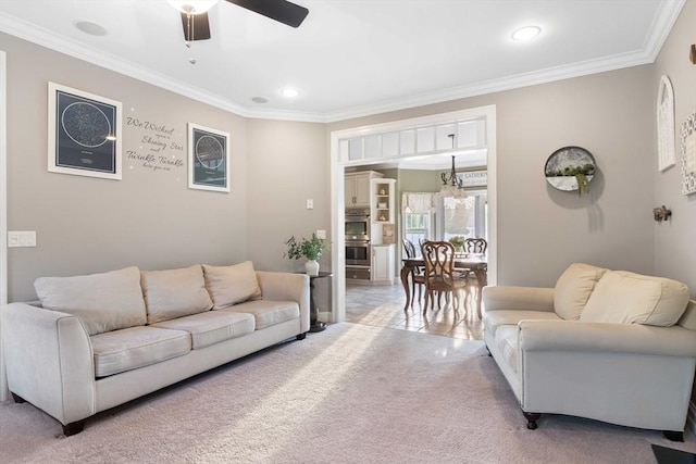 carpeted living room with ornamental molding and ceiling fan