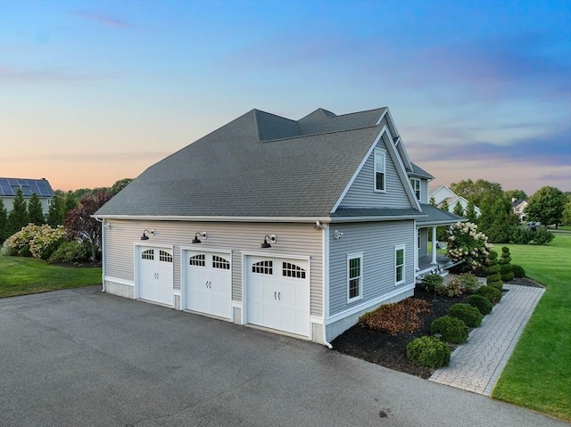 property exterior at dusk featuring a garage and a lawn