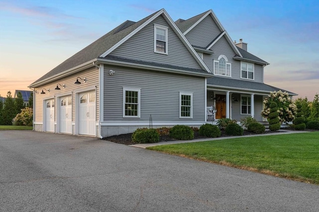 view of front facade featuring a garage, a lawn, and a porch