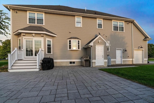 rear view of property with a garage and a patio