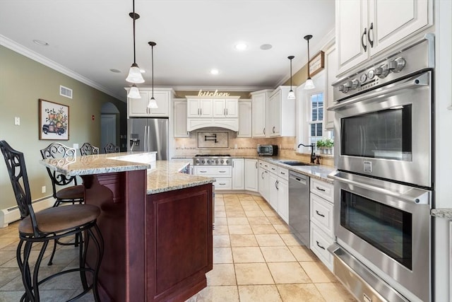 kitchen featuring appliances with stainless steel finishes, decorative light fixtures, sink, a breakfast bar area, and a center island