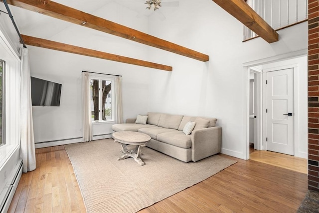 living room with baseboard heating, beam ceiling, and light wood-type flooring