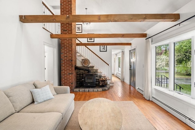 living room with a baseboard heating unit, a wood stove, and light wood-type flooring